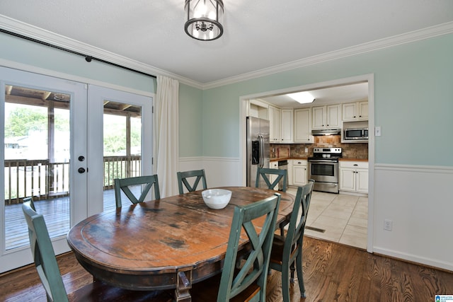 dining area with light wood-style flooring, ornamental molding, and french doors