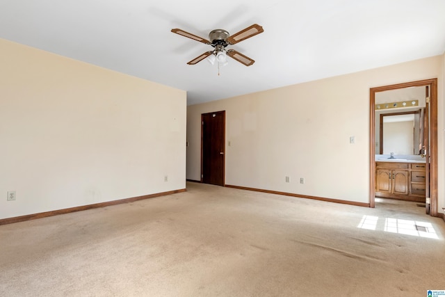 empty room with a sink, baseboards, a ceiling fan, and light colored carpet