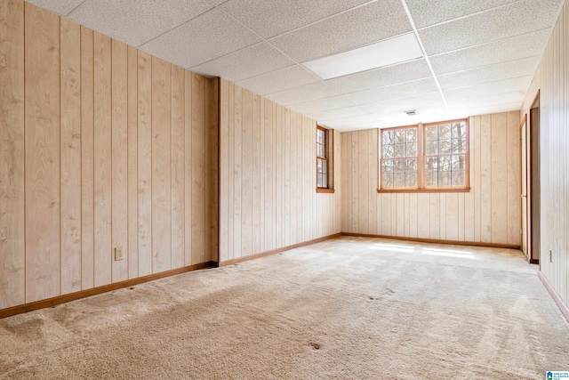 spare room featuring wooden walls, carpet floors, and a drop ceiling