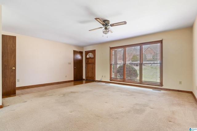 unfurnished living room with carpet, visible vents, baseboards, and ceiling fan