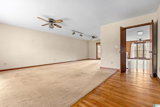 empty room featuring track lighting, ceiling fan, baseboards, and light wood-style flooring