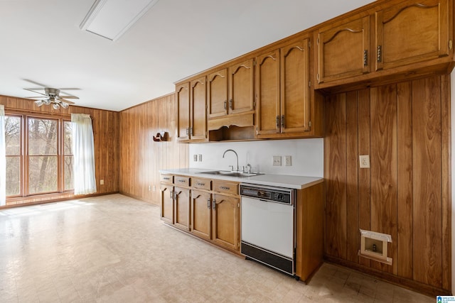 kitchen with brown cabinetry, a sink, white dishwasher, and light floors