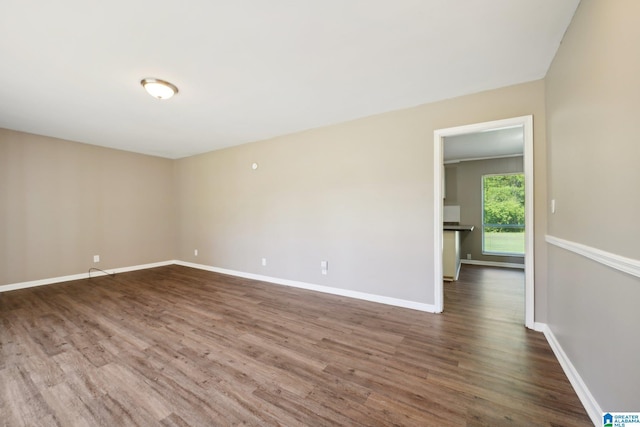 spare room with dark wood-style flooring and baseboards