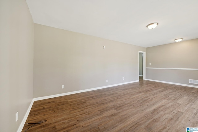 spare room featuring wood finished floors, baseboards, and visible vents