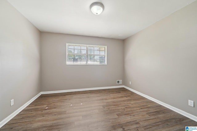empty room with visible vents, baseboards, and wood finished floors