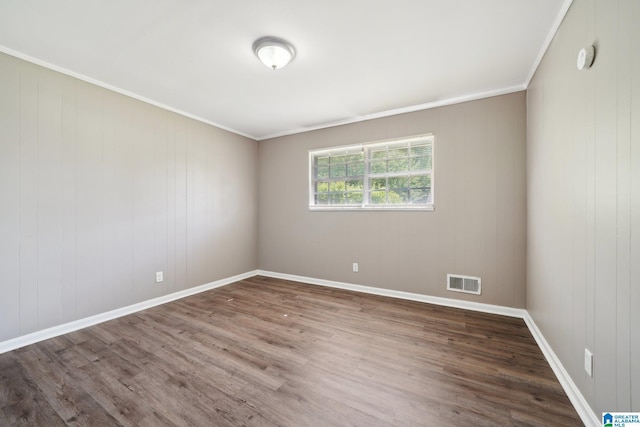empty room with ornamental molding, visible vents, and wood finished floors