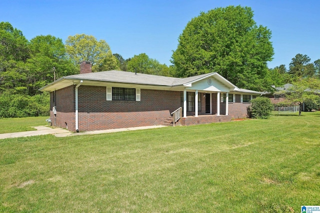 exterior space with brick siding, a yard, and a chimney