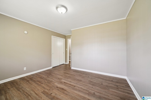 empty room featuring wood finished floors, baseboards, and ornamental molding