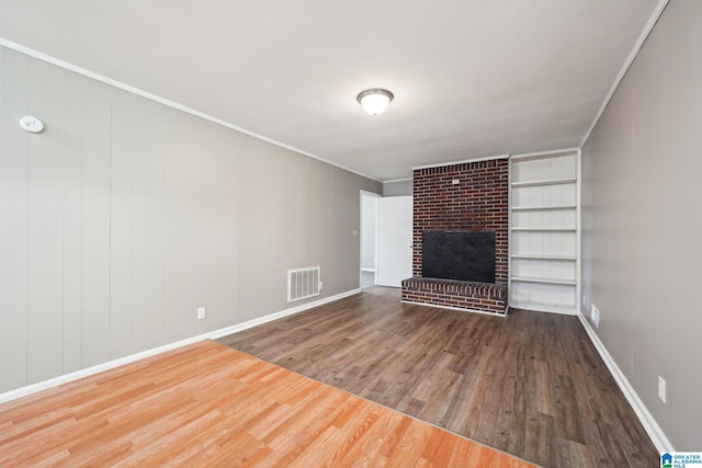 unfurnished living room with baseboards, ornamental molding, a fireplace, visible vents, and wood finished floors