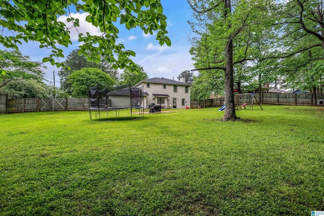 13563 Date St, Northport, AL 35475 - view of yard featuring a trampoline, a playground, and a fenced backyard