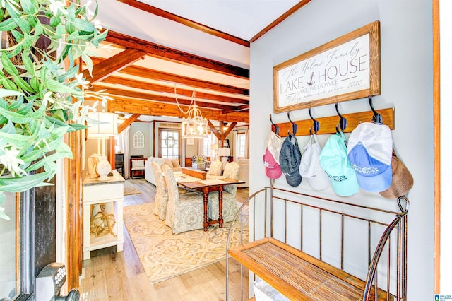 interior space with crown molding, wood finished floors, beamed ceiling, and an inviting chandelier