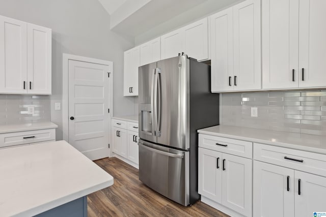kitchen with stainless steel fridge, light countertops, dark wood-style floors, white cabinetry, and decorative backsplash