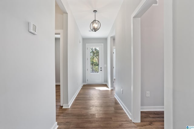 interior space featuring baseboards, a chandelier, and dark wood finished floors
