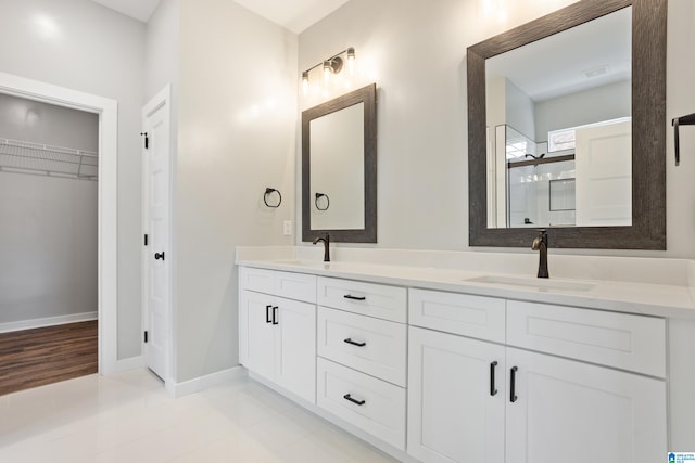 full bath with a shower stall, double vanity, a sink, and a walk in closet