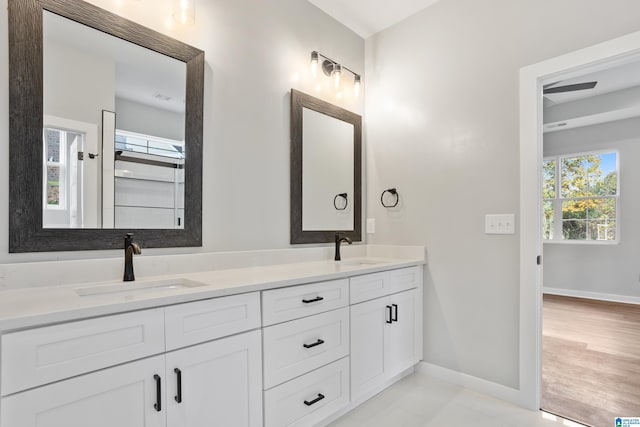 bathroom featuring double vanity, a sink, and baseboards