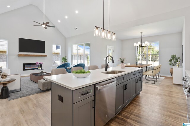 kitchen featuring gray cabinetry, open floor plan, dishwasher, and a sink