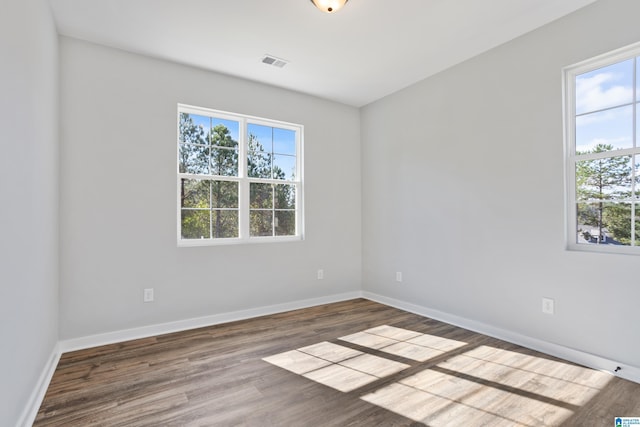 unfurnished room featuring visible vents, baseboards, wood finished floors, and a healthy amount of sunlight