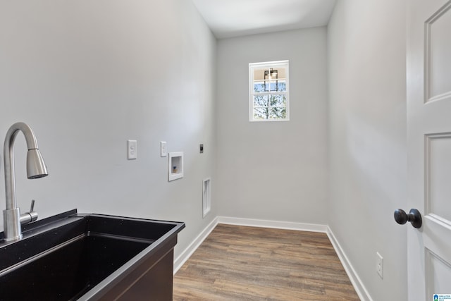 laundry area with laundry area, wood finished floors, hookup for an electric dryer, a sink, and baseboards