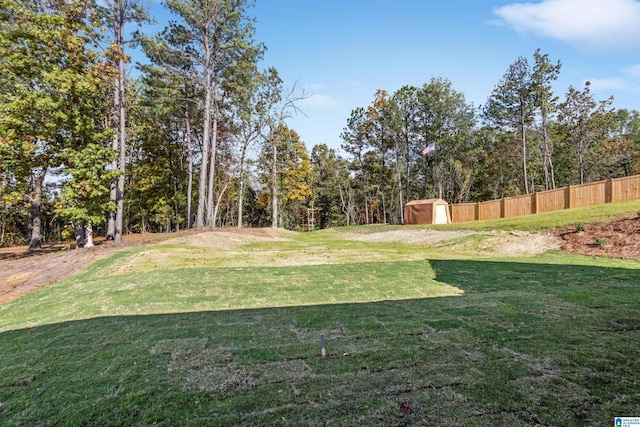 view of yard with an outbuilding, a storage unit, and fence