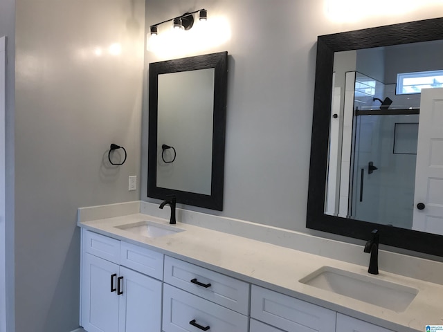 full bathroom featuring a sink, a shower stall, and double vanity