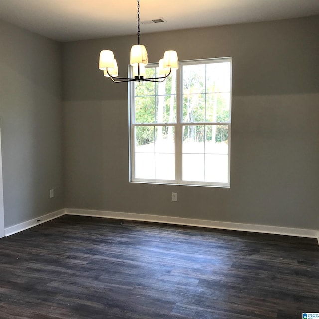 empty room with a chandelier, a wealth of natural light, visible vents, and dark wood-style flooring