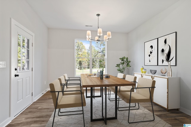 dining space featuring a notable chandelier, visible vents, baseboards, and wood finished floors
