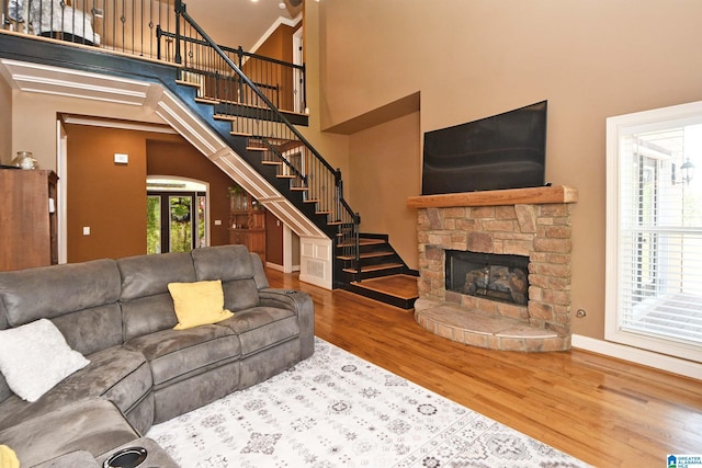 living room featuring stairway, a stone fireplace, baseboards, and wood finished floors