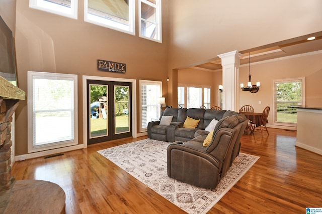 living area with wood finished floors, visible vents, a healthy amount of sunlight, and an inviting chandelier