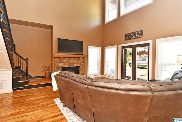 living room with a towering ceiling, a fireplace, light wood-style floors, and stairway