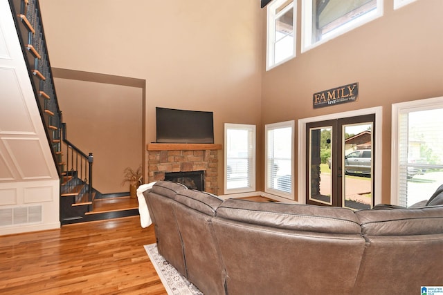 living room with stairway, a high ceiling, wood finished floors, visible vents, and a fireplace