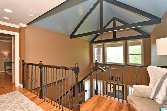 interior space with vaulted ceiling, wood finished floors, visible vents, and an upstairs landing