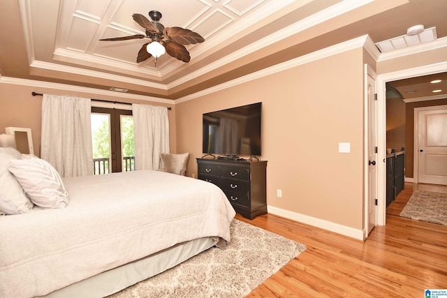 bedroom with ornamental molding, french doors, a tray ceiling, and light wood finished floors