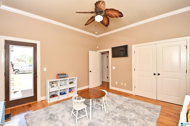 rec room featuring light wood-style flooring, crown molding, baseboards, and ceiling fan