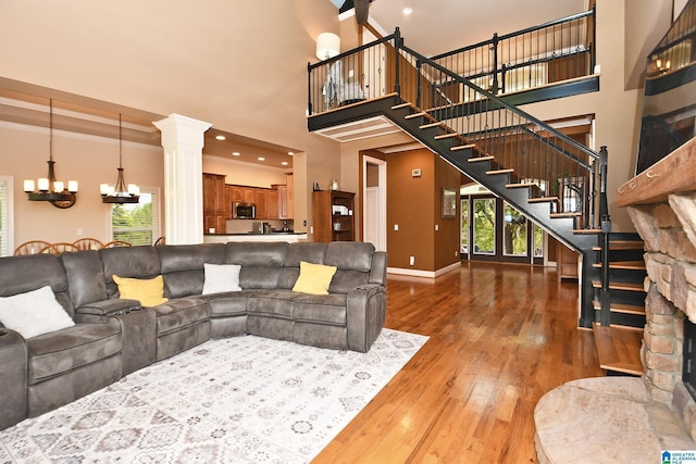 living room with baseboards, a chandelier, a high ceiling, stairs, and hardwood / wood-style flooring