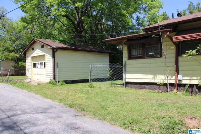 440 12th St W, Birmingham, AL 35208 - view of side of property featuring a detached garage, fence, an outdoor structure, and a lawn