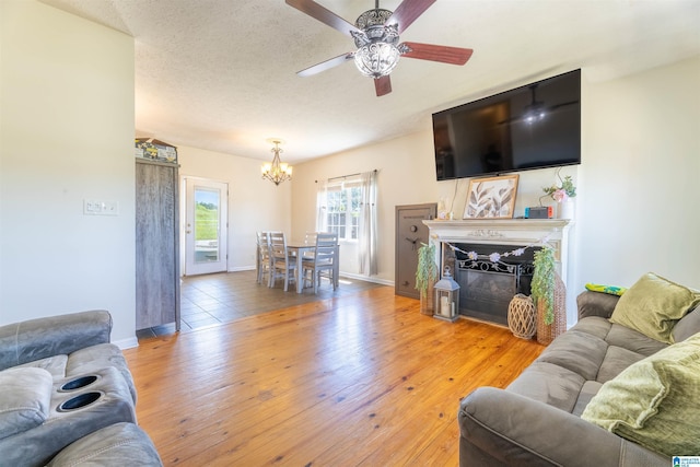 living area featuring hardwood / wood-style floors, baseboards, and ceiling fan with notable chandelier