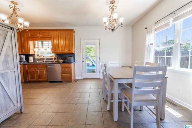 kitchen featuring dark countertops, dishwasher, brown cabinetry, and an inviting chandelier