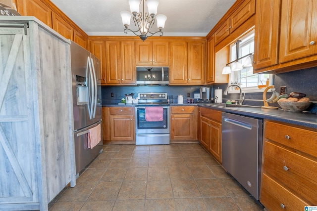 kitchen featuring stainless steel appliances, a sink, dark countertops, a chandelier, and brown cabinets