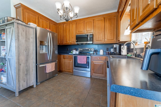 kitchen featuring brown cabinets, an inviting chandelier, appliances with stainless steel finishes, and a sink