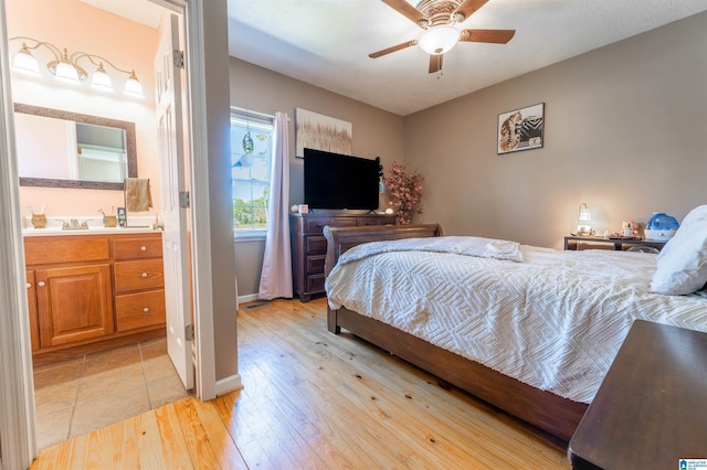 bedroom featuring light wood-type flooring, ensuite bathroom, baseboards, and ceiling fan