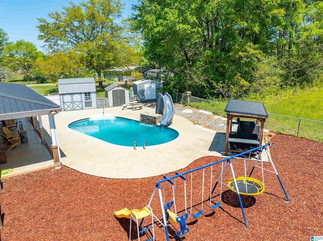 view of swimming pool featuring a water slide, a fenced backyard, a storage shed, an outdoor structure, and a patio
