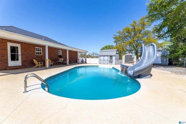 view of swimming pool with a fenced in pool, a water slide, a shed, an outbuilding, and a patio
