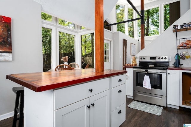 kitchen featuring stainless steel electric range oven, dark wood-style flooring, butcher block counters, and white cabinetry