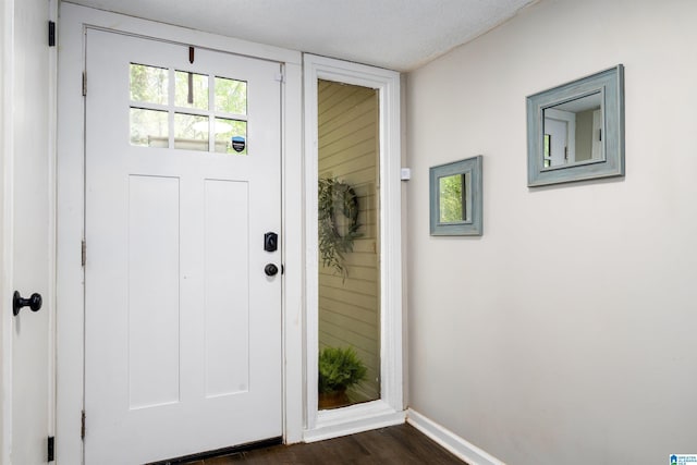 doorway with baseboards and dark wood-type flooring