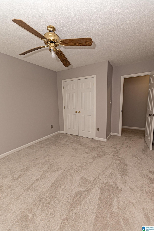 unfurnished bedroom featuring carpet floors, a textured ceiling, a ceiling fan, baseboards, and a closet