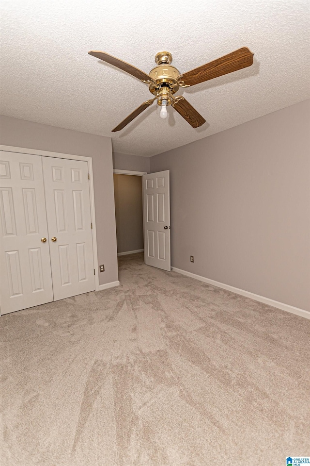 unfurnished bedroom with carpet floors, a closet, baseboards, ceiling fan, and a textured ceiling