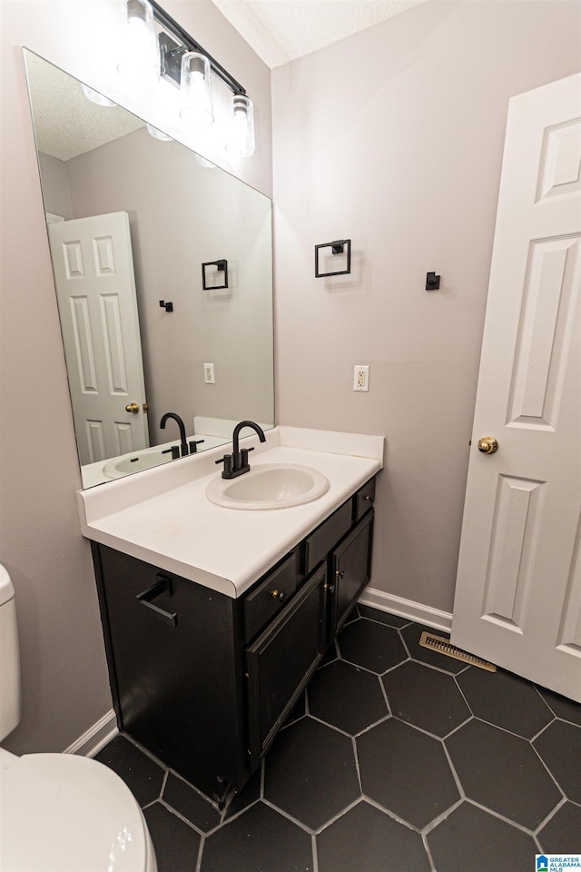half bathroom with toilet, baseboards, tile patterned flooring, and vanity