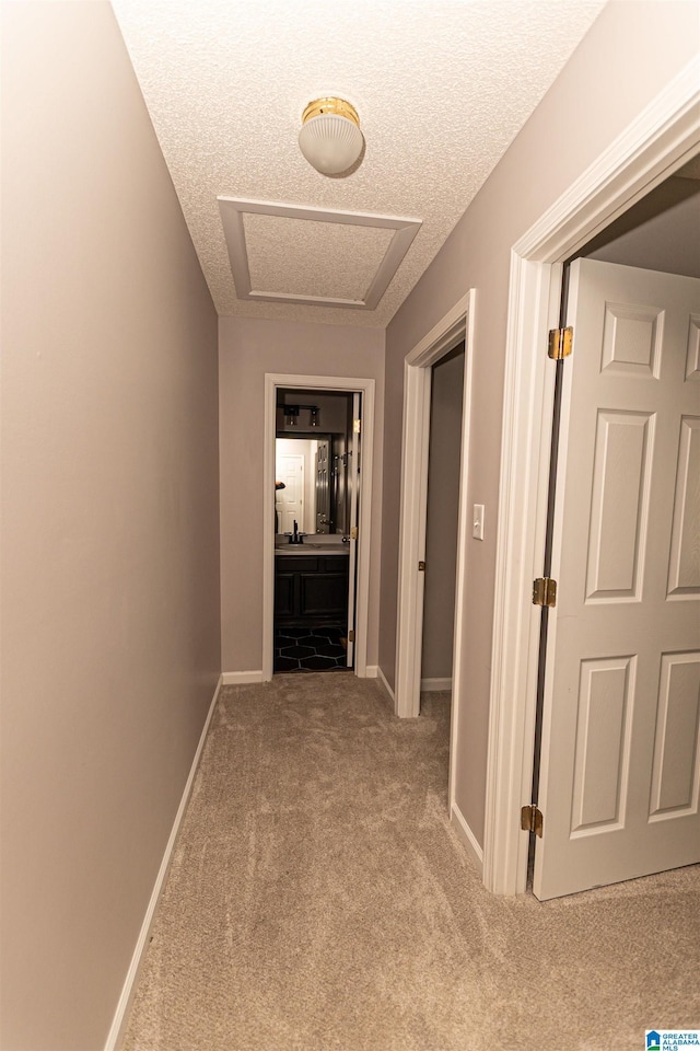 corridor featuring carpet floors, a textured ceiling, and baseboards