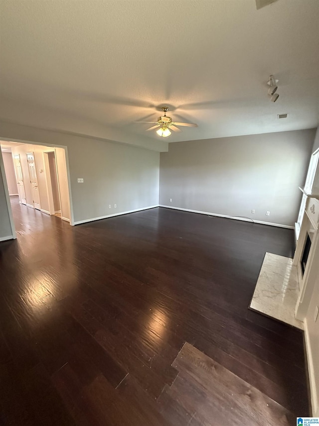 unfurnished living room featuring a ceiling fan, baseboards, a fireplace with flush hearth, and hardwood / wood-style flooring