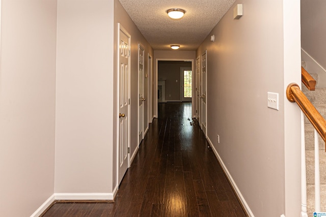 corridor with a textured ceiling, baseboards, and hardwood / wood-style floors
